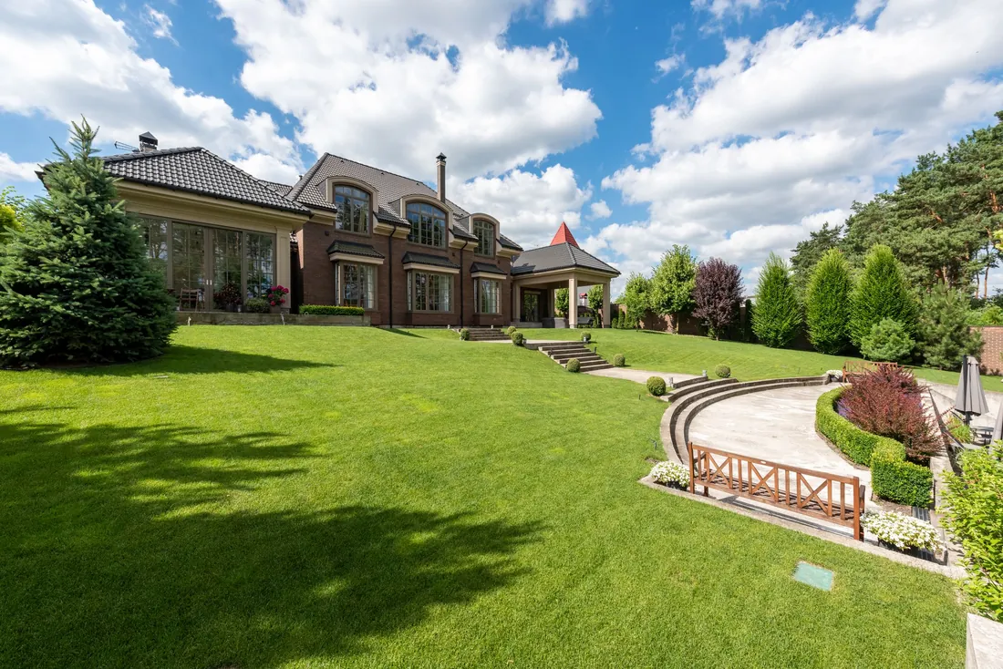 A large manicured lawn and landscaped garden in front of a home on a clear day